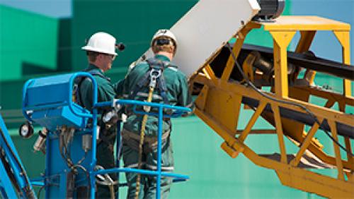 Two people on a forklift working on equipment